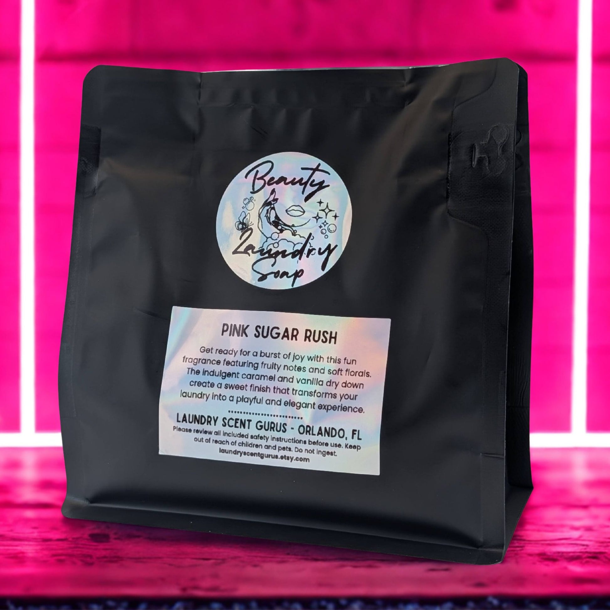 Black laundry scent packet with a label on a pink background