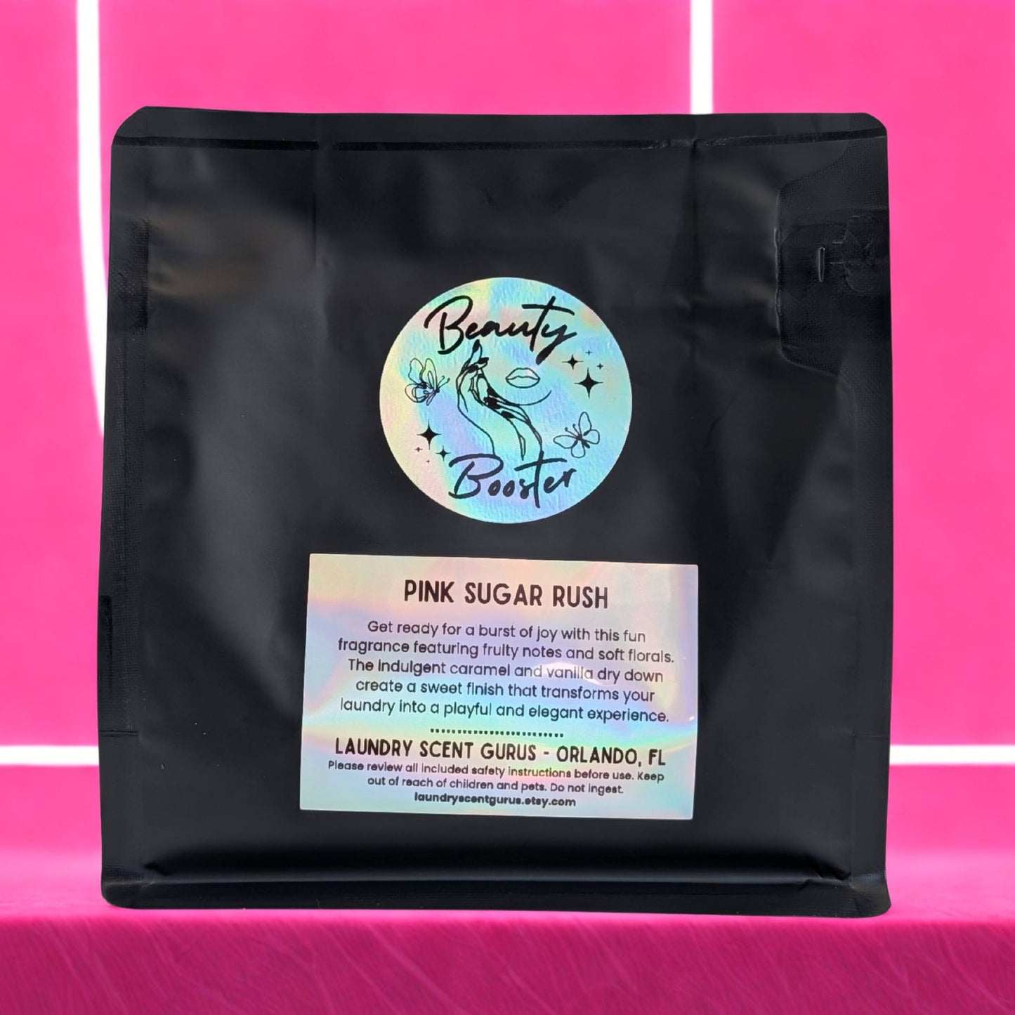 Black bag with 'Beauty Booster' label on a pink background
