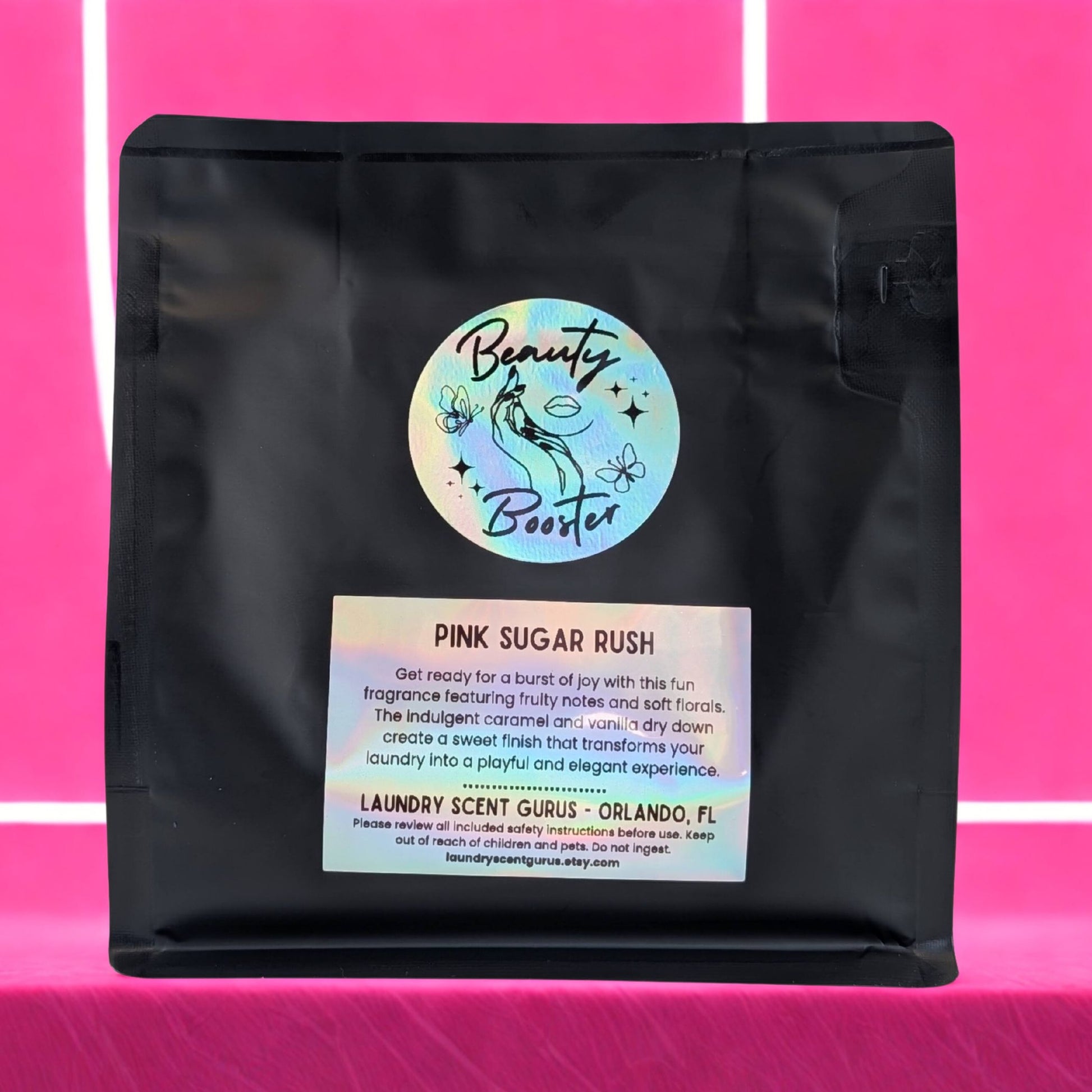 Black bag with 'Beauty Booster' label on a pink background