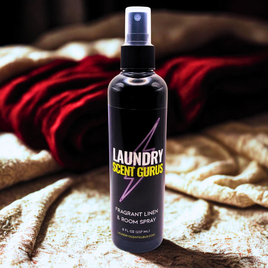 Bottle of Laundry Scent Gurus spray on a textured surface with cloths in the background