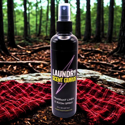 Bottle of Laundry Scent Gurus spray on a log with a forest background