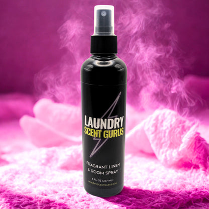 Black spray bottle labeled 'Laundry Scent Gurus' on a pink textured background
