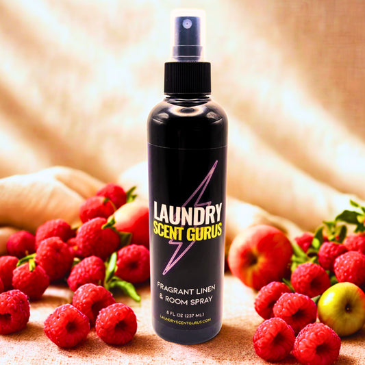 Bottle of Laundry Scent Gurus room spray with raspberries and apples on a fabric background