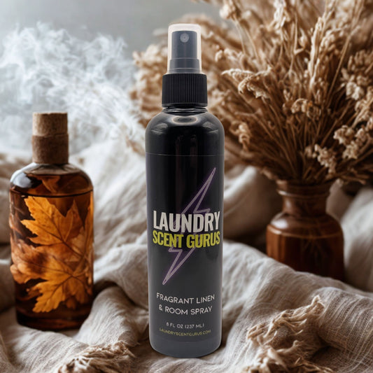 Laundry Scent Gurus spray bottle with decorative bottles and dried plants on a neutral background